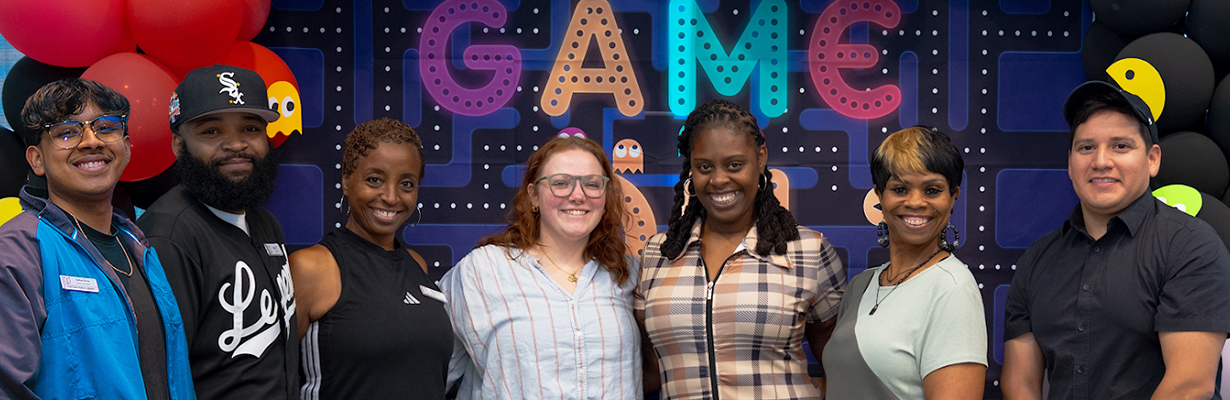 Middle and high school services staff pose in front of a video-game-themed display.