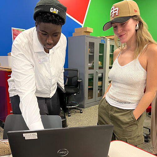 Intern helping a patron on a laptop in the Main Library Creative Studio.