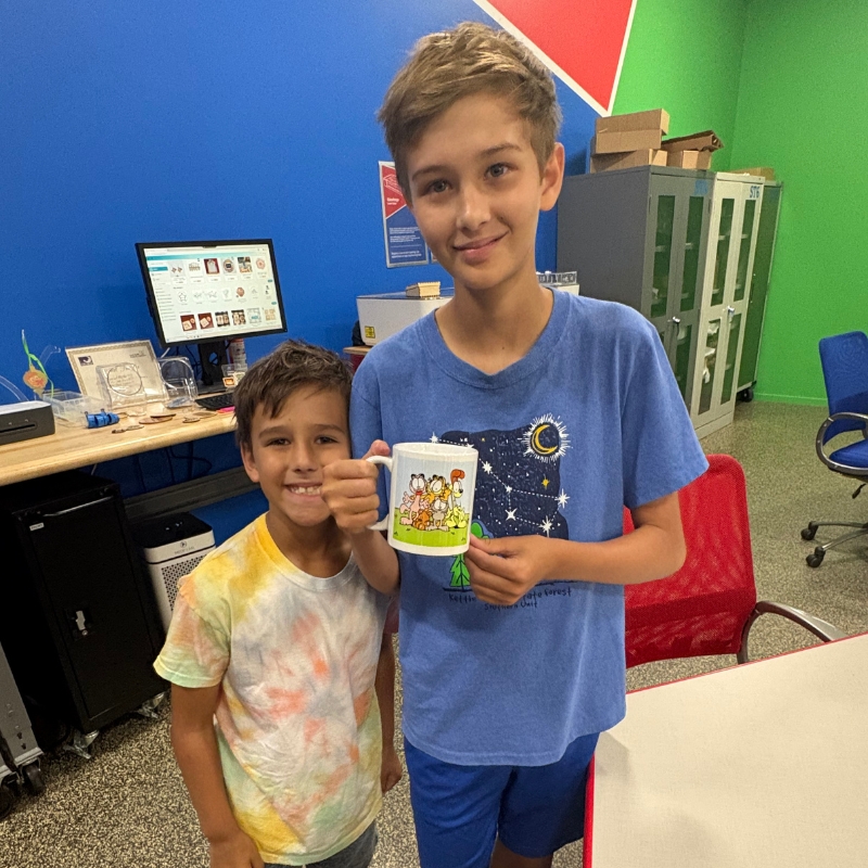 Two boys with one holding a mug made in the Creative Studio Makery.